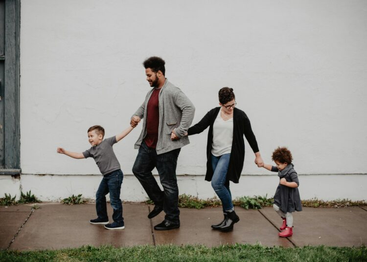 A family of four walking hand-in-hand, enjoying a day out.